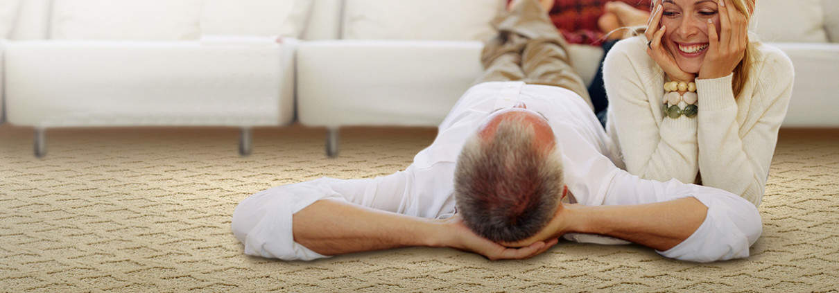 older man laying on a carpet with a woman next to him with upholstery in the background
